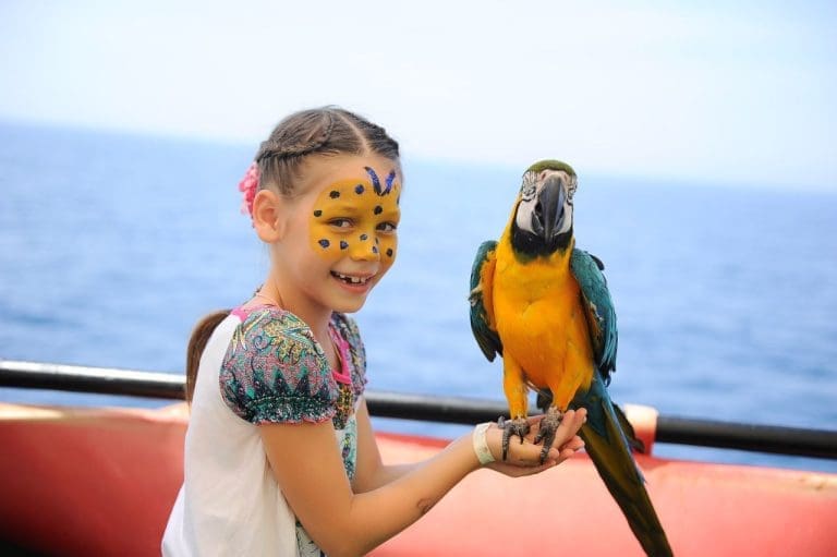 Child with painted face holding a parrot on Alanya pirate boat tour