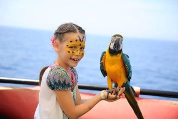Child with painted face holding a parrot on Alanya pirate boat tour